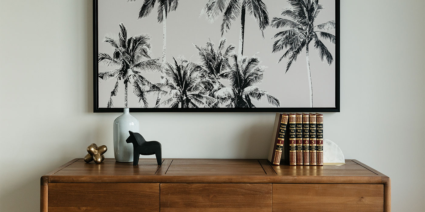 black and white palm tree print above wooden bookshelf